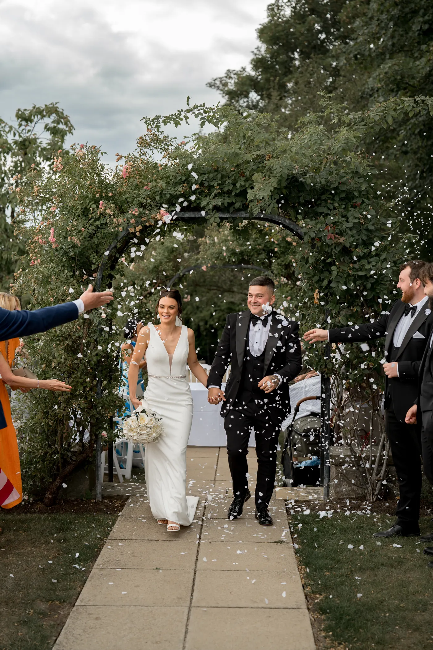 Couple kissing under a confetti-covered archway