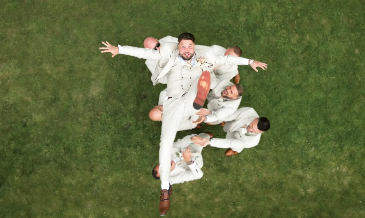 Groom in a colourful suit jumping for joy