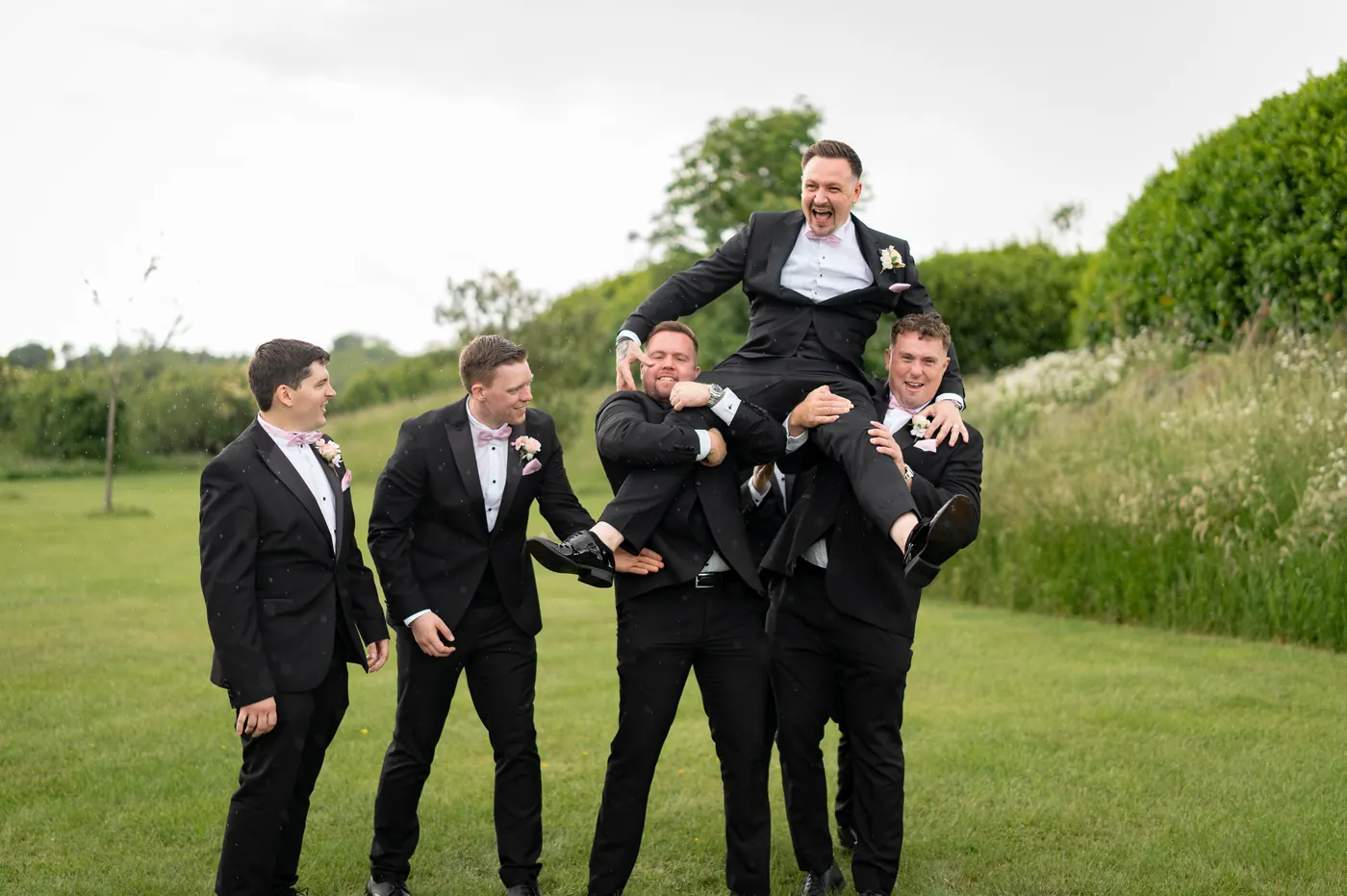 Groomsmen lifting the groom, laughing